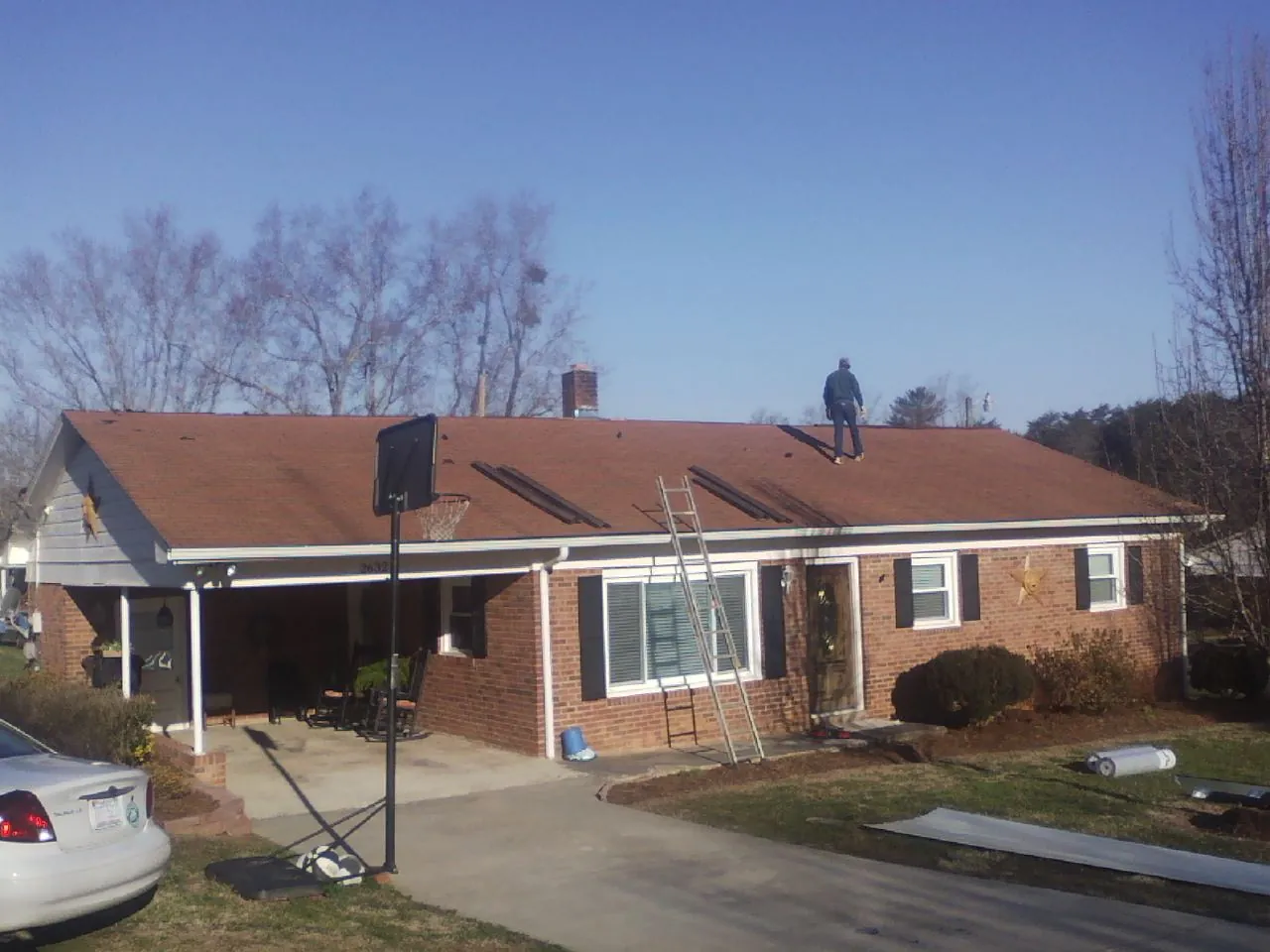 Roofer stripping a shingle roof on a brick ranch before metal panels in Monticello